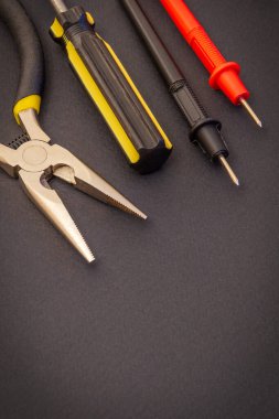 Elektrikçi araçları ve test terminalleri enerjili sistemleri veya iletişimi onarmak için siyah arkaplan üzerinde
