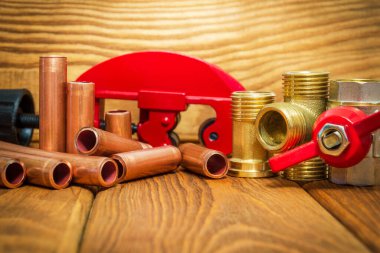 Kırmızı saplı yeni su topu vanası, pirinç tesisat ve eski ahşap tahtalardaki tesisat onarımı için bakır borular.