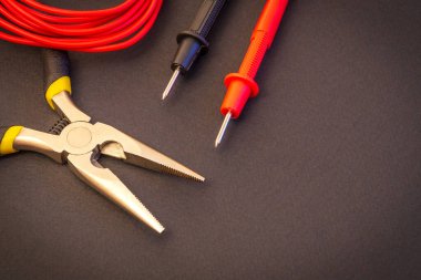 Elektrikçi araçları ve test terminalleri enerjili sistemleri veya iletişimi onarmak için siyah arkaplan üzerinde