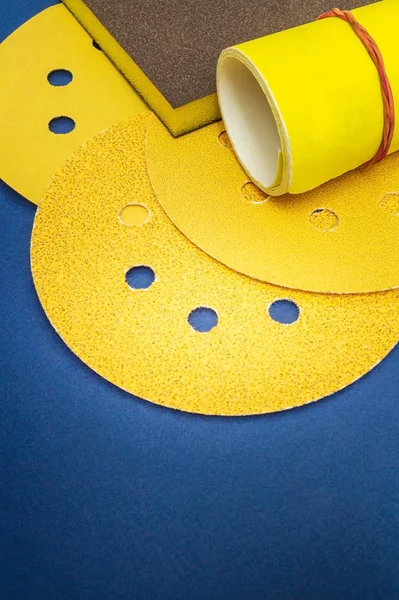 蓝色背景向导上的大量黄色研磨工具和砂纸用于研磨项目 — 图库照片