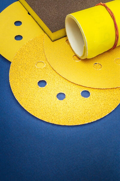 Big set of yellow abrasive tools and sandpaper on blue background wizard is used for grinding items