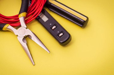 Elektrik aracı ve kırmızı kablo, enerjili sistemleri veya iletişimi onarmak için sarı arkaplan üzerinde