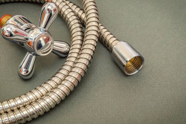 Su tesisatı musluğu ve koyu yeşil arkaplandaki hortum duşta yer değiştirmek için kullanılır.