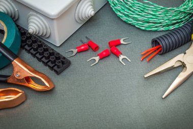 Gri arkaplandaki elektrik ekipmanlarının yenilenmesi veya onarılması için yedek parça, araç ve kablolar