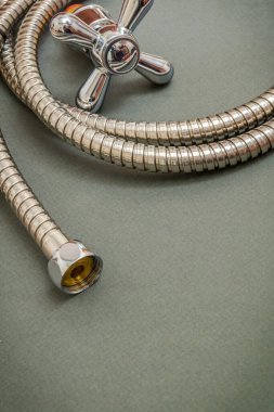 Su tesisatı musluğu ve koyu yeşil arkaplandaki hortum duşta yer değiştirmek için kullanılır.