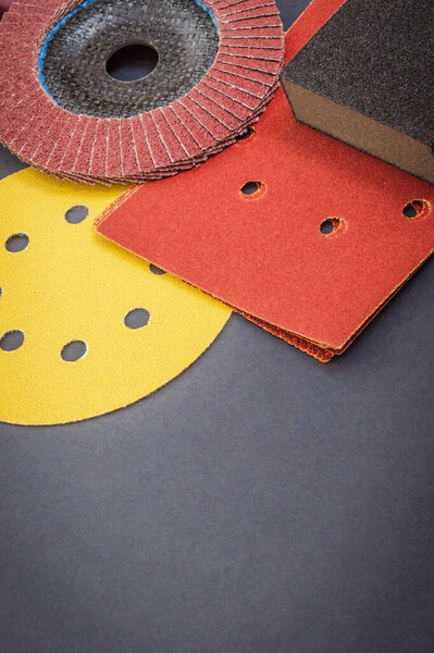 Для шлифования деталей используется набор абразивных инструментов и коричневая наждачная бумага на черном рабочем столе
