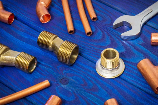 Copper water pipe fittings and tool for soldering plumbing concept or repair watersupply on vintage blue wooden boards