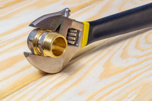 スペアパーツの修理または交換中に木製ボード上の真鍮継手と調整可能なスパナを配管 — ストック写真