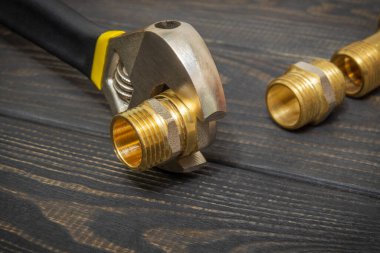 Boru tesisatı tesisatı ve ayarlanabilir anahtarlar yedek parçaların onarımı ya da yenilenmesi sırasında siyah tahta tahtalara yakın çekim yapıyor.