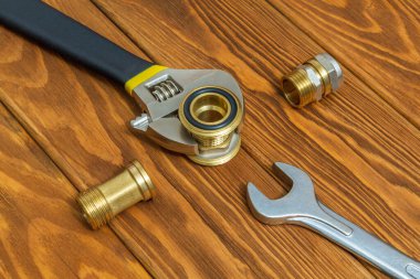 Boru tesisatı tesisatı ve ayarlanabilir anahtarlar yedek parçaların onarımı veya yenilenmesi sırasında eski ahşap tahtalara yakın plan