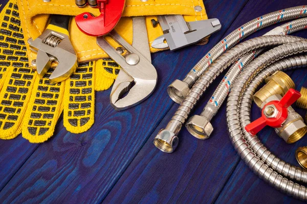 Plumbing tools in the yellow bag and spare parts on blue wooden boards are used to replace or repair — Stock Photo, Image