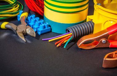 Siyah arkaplanda elektrik ekipmanlarının yenilenmesi veya onarılması için yedek parça, araç ve kablolar