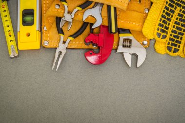 Poşetteki tesisat araçları ve gri masaüstündeki iş eldivenleri değiştirmek veya onarmak için kullanılır