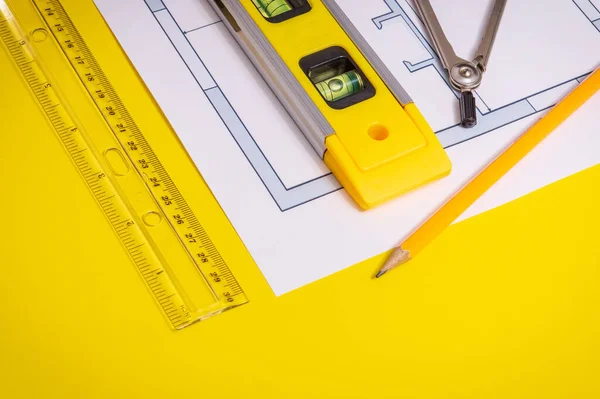 Accessories and drawing tools lie on building project or on the yellow working desktop