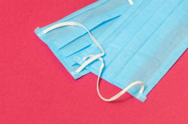 Kırmızı arka planda iki tıbbi doktor maskesi, grip ve korona virüsü koruması var.