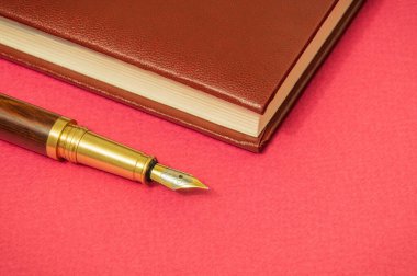 Ofis hala kırmızı masa. Not defteri ve yaldızlı kalem işadamı. Notlar için hazırlanın.