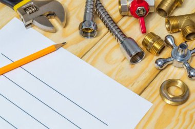 Tahtaya yedek parça ve aletlerle tesisat onarım planı çiziliyor.