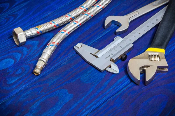 Necessary set of tools and hose for plumbers on wooden blue boards with space for advertising