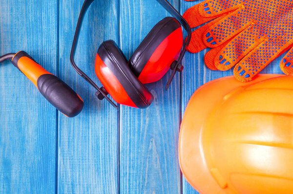 Оранжевая жесткая шляпа и инструмент на деревянных винтажных синих досках. Защитное оборудование для строителя
