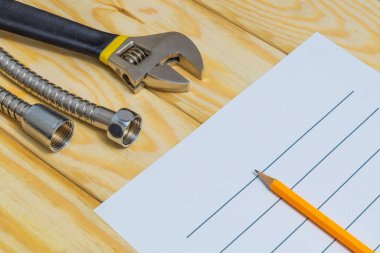 Ahşap arka planda yedek parça ve araçlarla tesisat onarım planı hazırlamak için çarşaf