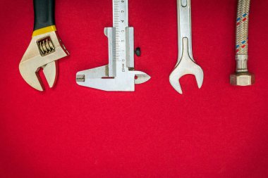 Kırmızı arka planda tesisatçılar için alet ve hortum seti ve reklam için yer var.