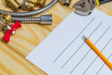 Tahtaya yedek parça ve aletlerle tesisat onarım planı çiziliyor.