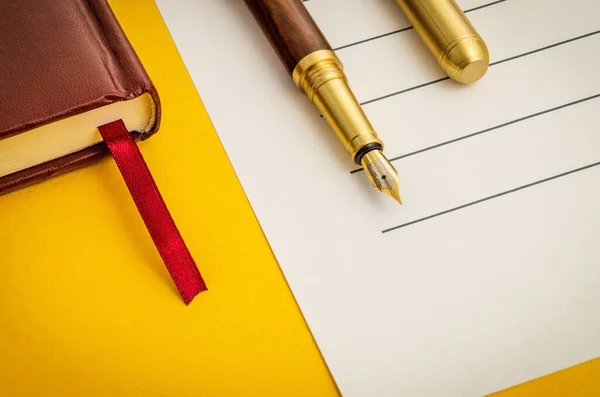 Office still life on yellow table with pen on sheet and notepad preparing for recordings