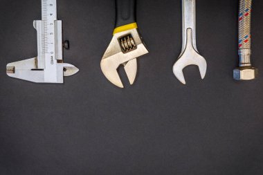 Siyah arka planda tesisatçılar için gerekli aletler ve hortum. Reklam için de yer var.