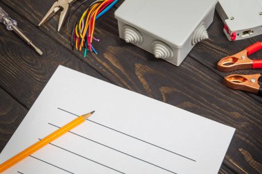 Koyu ahşap tahtalarda yedek parça ve aletlerle elektrik teçhizatının onarımı için plan çiziliyor