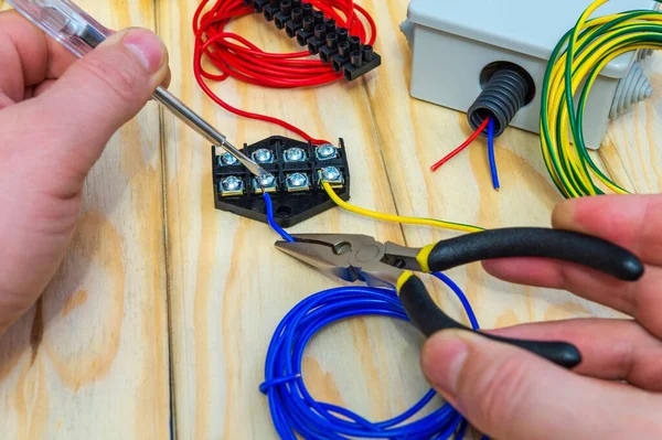 Üstat bağlanmak için farklı renkte elektrik ve kablolar tutuyor