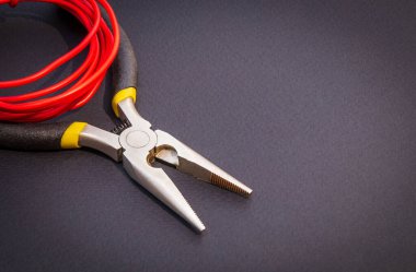 Elektrikçi için pense aracı ve kırmızı kablolar siyah arkaplan üzerindeki servis ve onarım kavramı