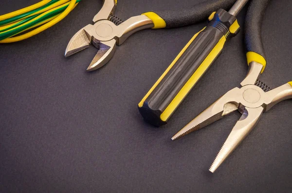 Electrician's tools and wire on a black background for repairing energized systems or communications