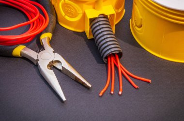 Siyah zemin üzerindeki elektrik ekipmanlarının yenilenmesi veya onarılması için yedek parça, araç ve kablolar