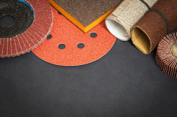 Big set of abrasive tool and multicolored sandpaper on black background, wizard is used for grinding items