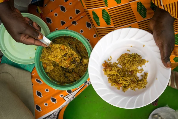 Schwarze Frau legt Pilau auf weißen Teller — Stockfoto