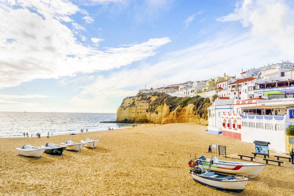 Sandy beach with colorful boats and cliffs and white architectur