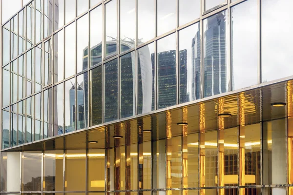 Arranha-céus refletidos na fachada de vidro do edifício moderno em Lond — Fotografia de Stock