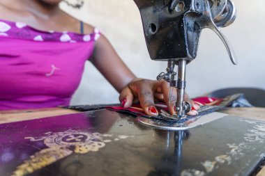 Mozambik 'te Afrika elbisesi dikmek için siyah dikiş makinesini kullanan terzi.