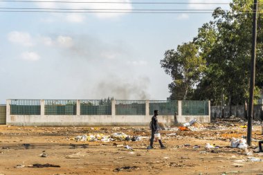 Maputo, Mozambik - 23 Mayıs 2019: Çöp dolu cadde boyunca yürüyen yumurta satıcısı