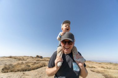 Sevimli, mutlu bir yaşındaki oğlu Eswatini, Afrika 'da babasının omuzlarına biniyor.