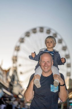 Eğlence parkında sırtında küçük oğluyla mutlu bir baba.