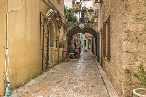 Budva, Montenegro - 22 de agosto de 2017: Old Town Street Budva, Montenegro. La primera mención de esta ciudad - hace más de 26 siglos. Vemos casas antiguas, una calle muy estrecha, cafés, tiendas . — Foto de Stock