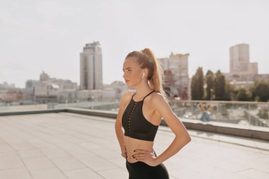 Güneş ışığında spor yaptıktan sonra dinlenen sportif kadın. O spor üniforma giyiyor ve müzik dinliyor 