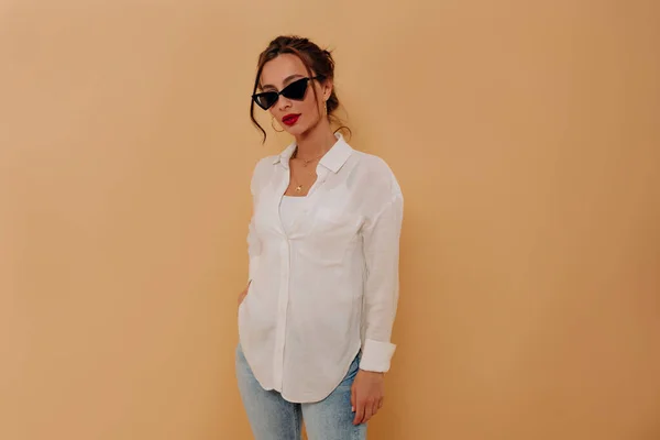 Elegante dama joven caucásica con pelo oscuro y labios rojos posando sobre un fondo aislado —  Fotos de Stock