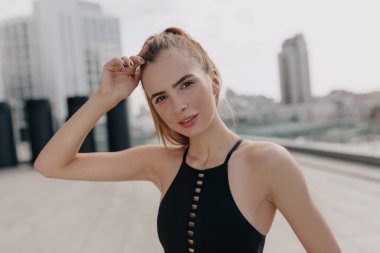  Spor giyimli atletik bir kadın büyük şehrin arka planında spor egzersizleri yapıyor ve ısınıyor.