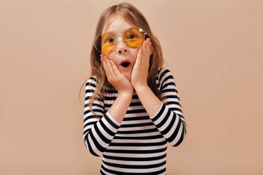 Açık ağız ile poz çıkardı gömlek giymiş hafif saç ile büyüleyici güzel küçük 6 yaşında kız ve Çek eller tutar 