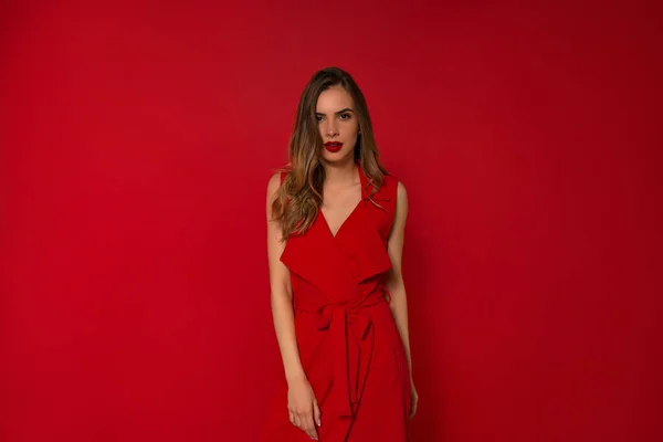 Elegante modelo caucásico con vestido rojo de pie con sonrisa encantadora con vestido de noche . — Foto de Stock