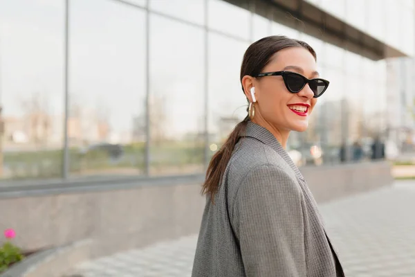 Moderne zakenvrouw dragen jas en zonnebril met rode lippen gaan in zakenwijk tijdens koffie snavel — Stockfoto