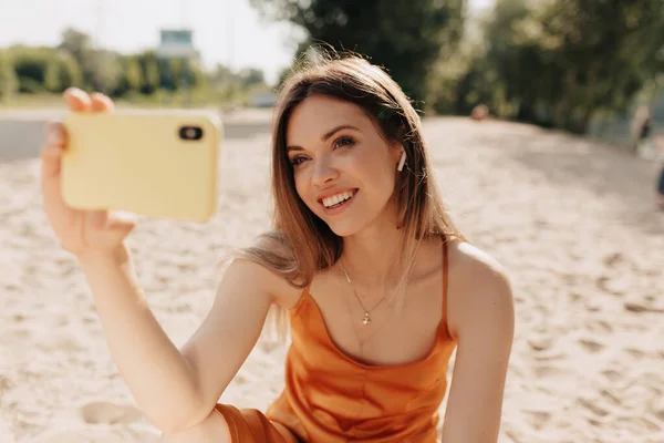 Funny Sunny Girl bär orange kläder att göra Selfie på sommaren stranden i solljus — Stockfoto