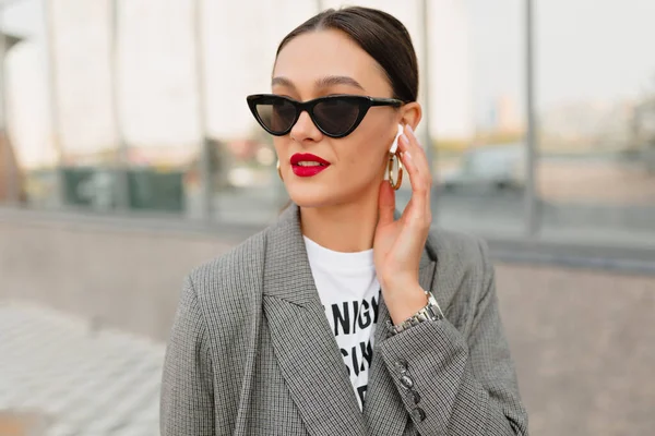 Foto al aire libre de modelo femenina feliz tiene una pausa para el café y en el distrito de negocios de la ciudad, escuchando música — Foto de Stock